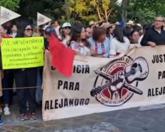 Familiares de periodista Leyva protestan en desfile de delegaciones en exigencia de justicia; grupo de choque intentó bloquearlos